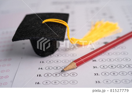 Graduation gap hat and pencil on answer sheet background, Education study testing learning teach concept. Graduation gap hat and pencil on answer sheet background, Education study testing learning teach concept. 81527779