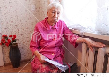 Woman holding cash in front of heating radiator. Payment for heating in winter. Selective focus. Woman holding cash in front of heating radiator. Payment for heating in winter. Selective focus. 81528868