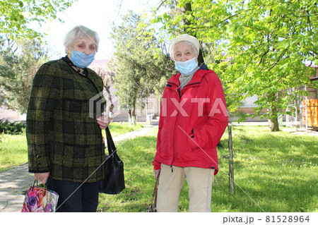Happy positive smiling senior woman takes off protective medical mask from face outdoors 81528964