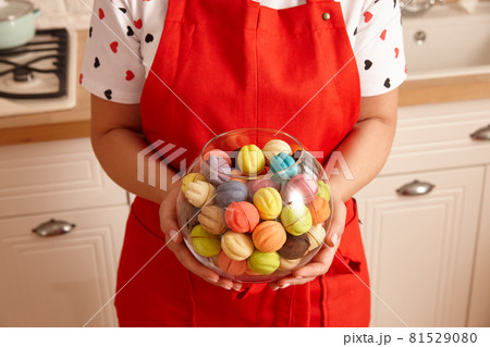 Woman in red apron holding glass bowl with sweets Woman in red apron holding glass bowl with sweets 81529080