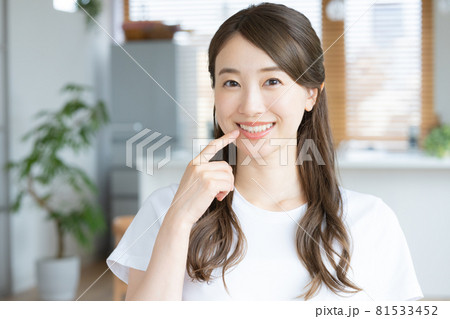 自宅のリビングで歯のチェックをする若い女性 81533452