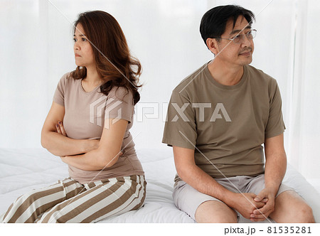 Portrait of middle-aged Asian lover couple sitting on a bed at home and arguing about the family financial problem. Woman crossed arm to show her disappointment. Concept of problems in a relationship Portrait of middle-aged Asian lover couple sitting on a bed at home and arguing about the family financial problem. Woman crossed arm to show her disappointment. Concept of problems in a relationship 81535281