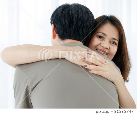 Horizontal back view portrait of senior Asian husband hugging his wife. A lovely couple standing closely and embracing each other with a warm hug. Concept of a romantic relationship in elderly 81535747
