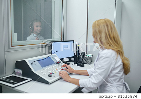 Girl in headsets standing in the soundproof booth Girl in headsets standing in the soundproof booth 81535874