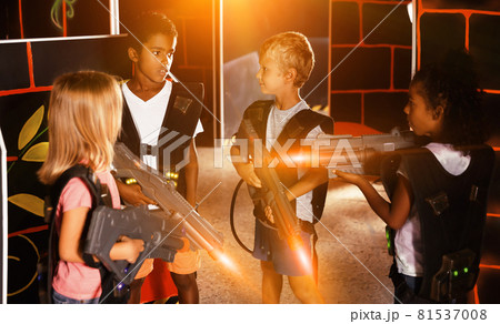 Group of glad pleasant teenagers with laser guns having fun on dark lasertag arena 81537008