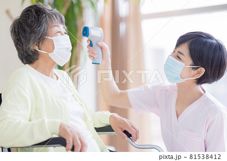 介護イメージ　非接触体温計で検温する医療従事者 81538412