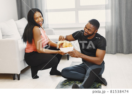 Handsome Afro American couple sitting with fruitsat home Handsome Afro American couple sitting with fruitsat home 81538474