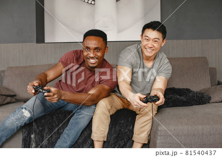 Two friends playing Playstation in the living room Two friends playing Playstation in the living room 81540437