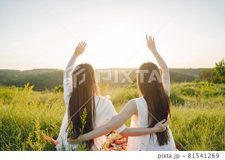 Portrait of two sisters in white dresses with long hair in a field Portrait of two sisters in white dresses with long hair in a field 81541269