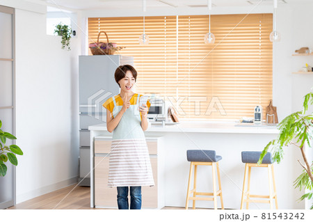 キッチンに立つ笑顔のミドル女性 81543242