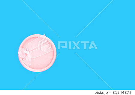 Round pink gift box with pink ribbon on a light blue background with place for text. 81544872
