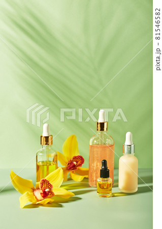 Cosmetic care products in glass bottles with orchid flowers - serums, cream, gel, oils. Concept for face and body care, wellness and spa, tropical relaxation 81546582