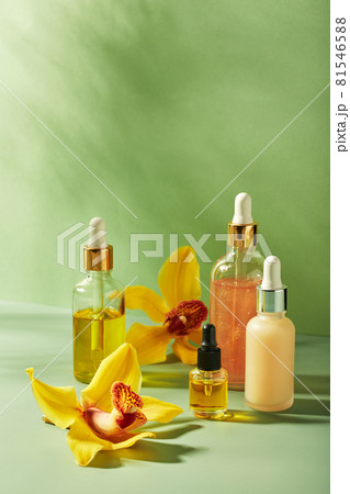 Cosmetic care products in glass bottles with orchid flowers - serums, cream, gel, oils. Concept for face and body care, wellness and spa, tropical relaxation. 81546588