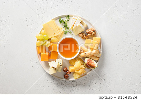Cheese platter with grapes, nuts, figs on a white. 81548524