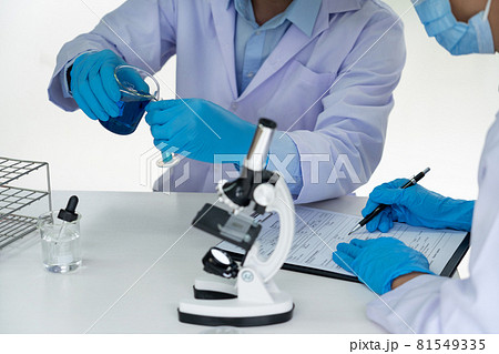 Attractive young scientist team in lab coat and safety goggles working with analysing test trial or investigations with test tubes in laboratory. 81549335