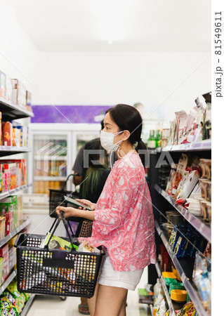 Asian woman with protective face mask with shopping basket in department store. Asian woman with protective face mask with shopping basket in department store. 81549611