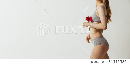 Portrait of young attractive woman holding flower as symbol of tenderness isolated over gray studio background. Natural beauty, authenticity concept. Flyer Portrait of young attractive woman holding flower as symbol of tenderness isolated over gray studio background. Natural beauty, authenticity concept. Flyer 81552585