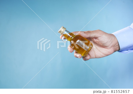 hand holding a bottle of olive oil against blue background hand holding a bottle of olive oil against blue background 81552657