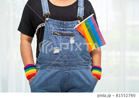 Asian lady wearing blue jean jacket or denim shirt and holding rainbow color flag, symbol of LGBT pride month celebrate annual in June social of gay, lesbian, bisexual, transgender, human rights. Asian lady wearing blue jean jacket or denim shirt and holding rainbow color flag, symbol of LGBT pride month celebrate annual in June social of gay, lesbian, bisexual, transgender, human rights. 81552760