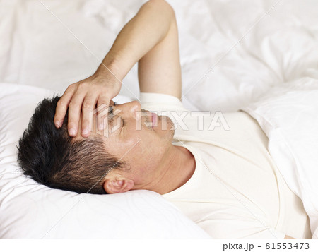 asian man lying on back in bed hand on forehead asian man lying on back in bed hand on forehead 81553473