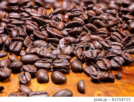 Macro photography top view of a heap fresh roasted coffee beans on a wooden background. High resolution detailed close up of brown roasted coffee beans on tropical wood table. Wallpaper image Macro photography top view of a heap fresh roasted coffee beans on a wooden background. High resolution detailed close up of brown roasted coffee beans on tropical wood table. Wallpaper image 81558715