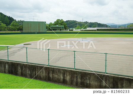 雨上がりで曇天模様の球場のグラウンドに水溜まりが残っている光景 81560233