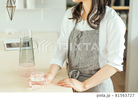 女性がキッチンで水の入ったグラスを持っている woman water hand 女性がキッチンで水の入ったグラスを持っている woman water hand 81563727