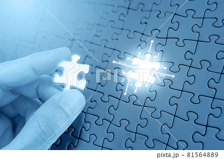 Hand filling missing piece of jigsaw puzzle 81564889