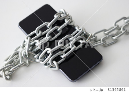 Black smartphone wrapped in metal chain closeup Black smartphone wrapped in metal chain closeup 81565861