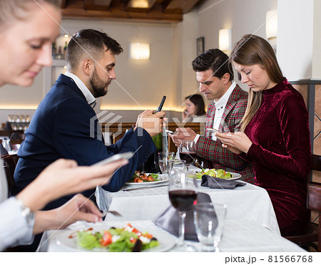 Modern young people with phone at restaurant Modern young people with phone at restaurant 81566768