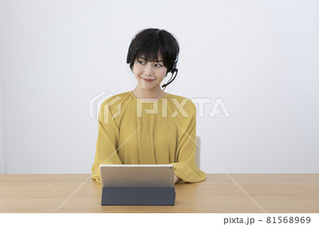 ヘッドホンをして部屋でリモートワークをする若い女性 81568969