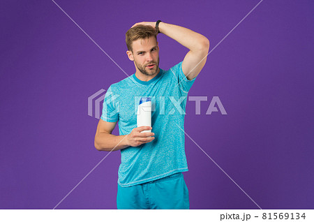 Man on confident face touching his hair, violet background.  81569134