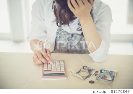 女性が部屋で電卓とお金を出して頭を抱えている woman money 女性が部屋で電卓とお金を出して頭を抱えている woman money 81570847