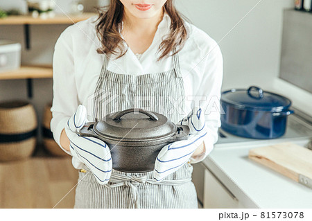 キッチンで女性がミトンをつけて両手で鍋を持っている　woman kitchen 81573078