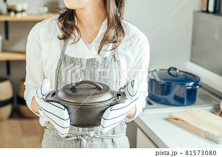 キッチンで女性がミトンをつけて両手で鍋を持っている　woman kitchen 81573080