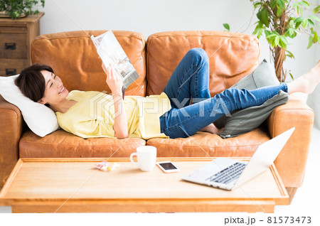 ソファーに寝転がって雑誌を読む女性 ソファーに寝転がって雑誌を読む女性 81573473