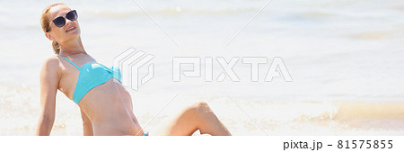 Young woman in sunglasses and swimsuit lying on beach Young woman in sunglasses and swimsuit lying on beach 81575855