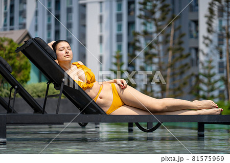 sexy girl in a swimsuit sunbathes and enjoys relaxing by the pool 81575969