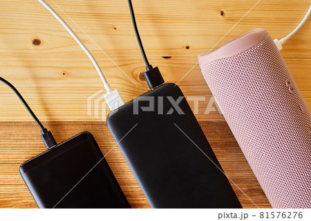 Powerbank charges smartphone and portable speaker using usb. Close-up, selective focus Powerbank charges smartphone and portable speaker using usb. Close-up, selective focus 81576276