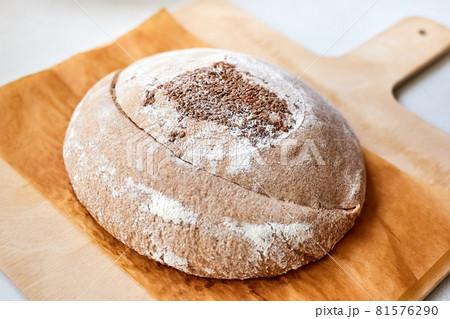 Homemade round rye bread with flax seeds on a wooden board. Close-up, selective focus 81576290