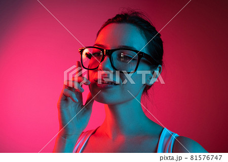 Cropped portrait of young beautiful girl in glasses on gradient pink red background Cropped portrait of young beautiful girl in glasses on gradient pink red background 81576747