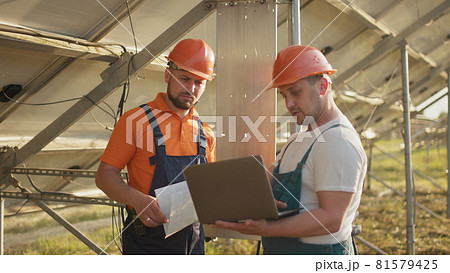 Engineer man inspects construction of solar cell panel or photovoltaic cell by electronic device. Industrial Renewable energy of green power. Technicians with tablet checking the solar panels 81579425