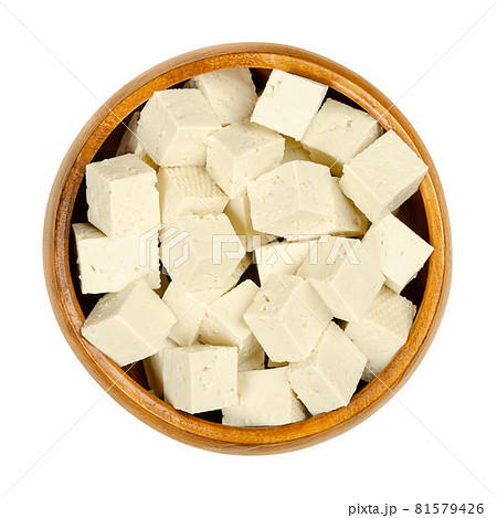 Cubes of white tofu, in a wooden bowl. Diced bean curd, coagulated soy milk, pressed into white blocks of different softness. A component of Asian cuisine, and a meat substitute. Close-up, from above. Cubes of white tofu, in a wooden bowl. Diced bean curd, coagulated soy milk, pressed into white blocks of different softness. A component of Asian cuisine, and a meat substitute. Close-up, from above. 81579426