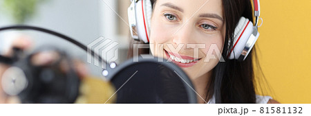 Portrait of young woman in headphones in front of microphone Portrait of young woman in headphones in front of microphone 81581132