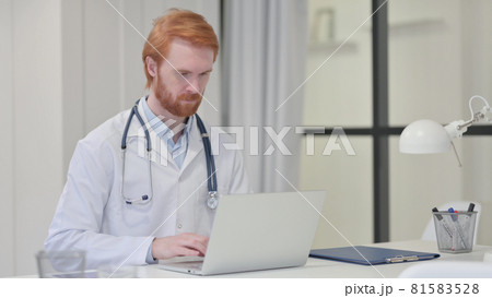 Redhead Male Doctor Working on Laptop Redhead Male Doctor Working on Laptop 81583528