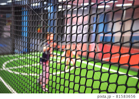 Blurred children are playing behind the net at indoor playground in activity park. 81583656
