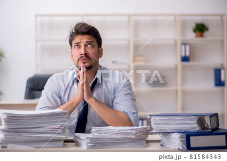 Young male employee unhappy with excessive work in the office 81584343