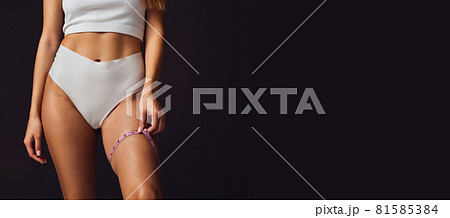 Cropped body. Slim tanned beautiful woman in underwear isolated over dark brown background. 81585384
