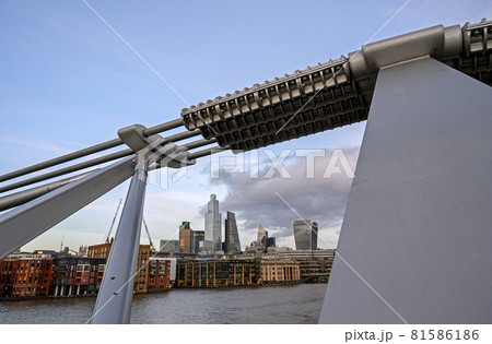 City of London in the UK. View over the River Thames to the city of London framed by the Millennium Bridge. Cityscape of the business district with skyscrapers and clouds in London, England 2020. City of London in the UK. View over the River Thames to the city of London framed by the Millennium Bridge. Cityscape of the business district with skyscrapers and clouds in London, England 2020. 81586186