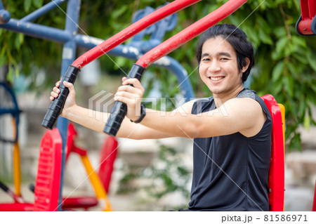 In a public park, young men exercise in sports on an outdoor workout equipment. 81586971